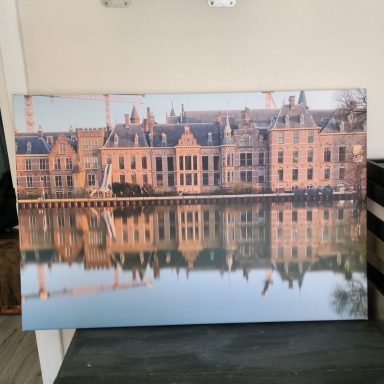 Historisch gebouw met reflectie in het water en een heldere lucht.