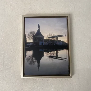 Zonsopgang bij een kerk, weerspiegeld in het rustige water.